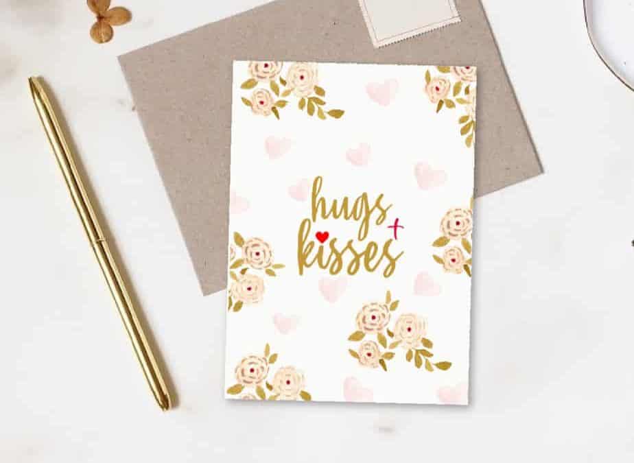 Free Printable Hugs and Kisses card on top of craft paper envelope mock up of greeting card